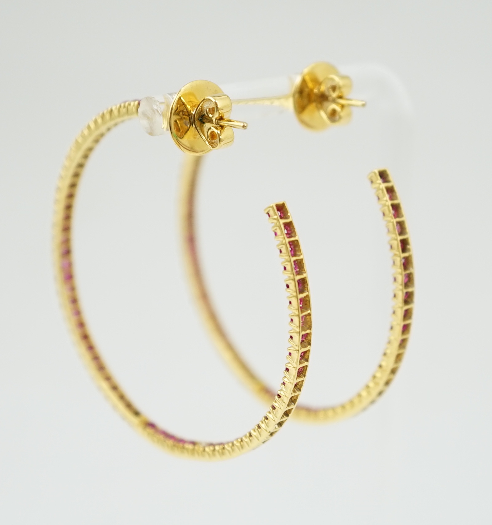 A large pair of gold and ruby chip set hoop earrings